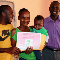 Herve Delisma (left), the assistant coordinator of the MPP-FONDAMA Yard Garden Program, and Viljean Louis (right), the coordinator for the Farmer Movement of Bayonnais, presenting a certificate of achievement to Aliette Baptiste, from the community of Demòn, for the excellent development of her yard garden.
