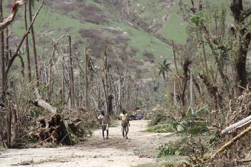 Two residents of the Grand Anse department of Haiti walk along a muddy road, framed by the devastation of trees and vegetation destroyed by Hurricane Matthew on Oct. 4, 2016.