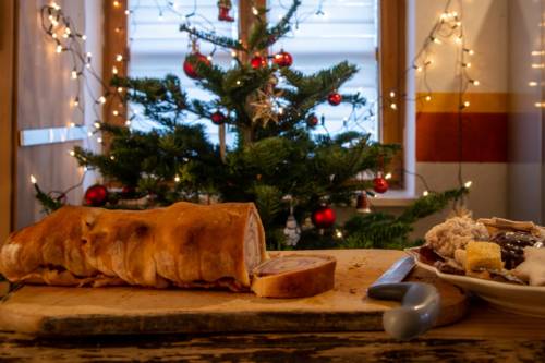 Bread and cookies lie on a table in front of a Christmas tree