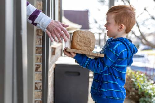 Little boy bringing a loaf of homemade bread to a neighbor