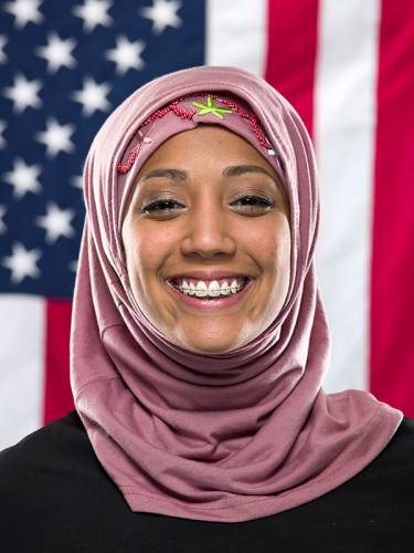 Photo of smiling muslim woman in front of U.S. flag.
