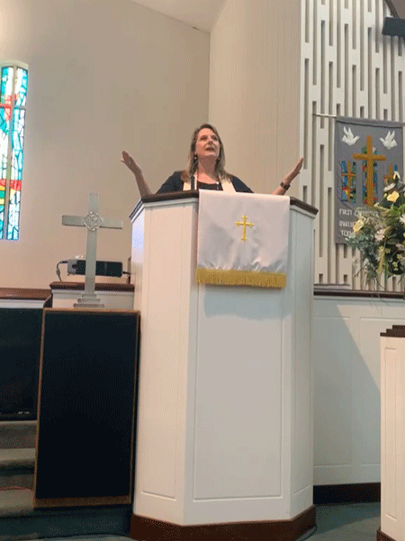Rev. Gini Norris-Lane, standing at the pulpit.