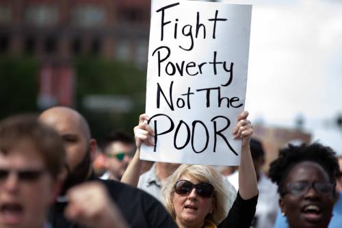 woman holding sign fight poverty not the poor