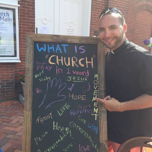 Rev. Fernando Rodríguez Quiñones displays a sign with responses from Peach Festival attendees