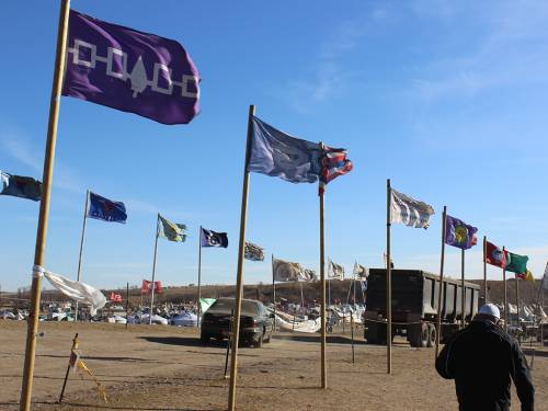 Tribal flags at At Oceti Sakowin Camp show the strength of the winter winds as they begin to move into the area. (Photo by Rick Jones)