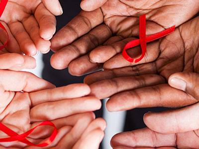 Connecting hands holding HIV/AIDS red ribbons