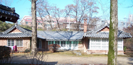Photograph of the YAV House on the Hannam University campus with trees and a large university building in the background.