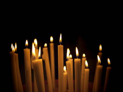 A bunch of lit candles against a black background.