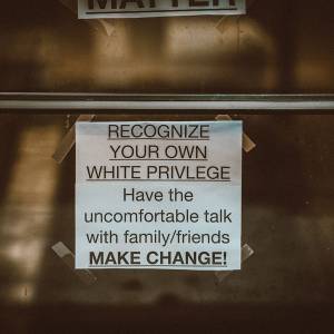 Sign taped to window that says: Recognize Your Own White Privilege: Have the uncomfortable talk with family/friends. Make Change!