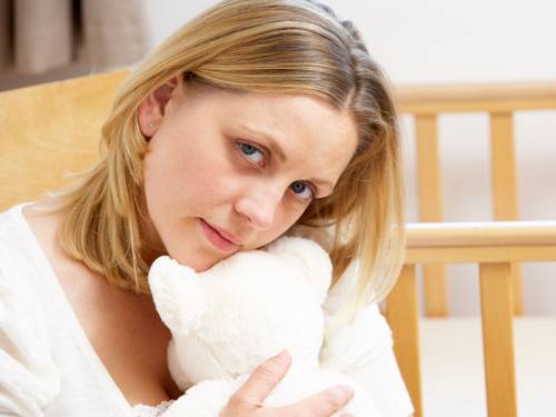 sad woman clutching a teddy bear