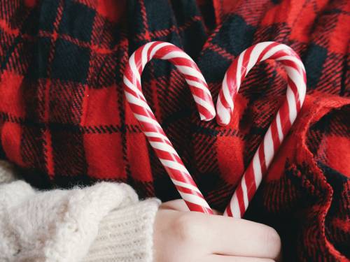 Girl holding 2 candy canes to make the shape of a heart.