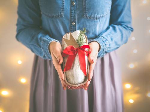 Woman holding a loaf of homemade Christmas bread tied in a red ribbon