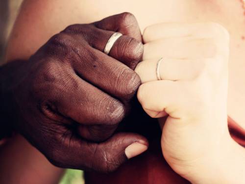 Hands of interracial couple with wedding rings