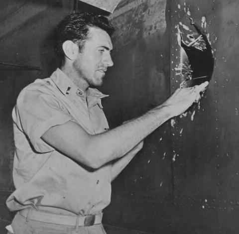 Louis Zamperini examines a hole in his B-24D Liberator Super Man