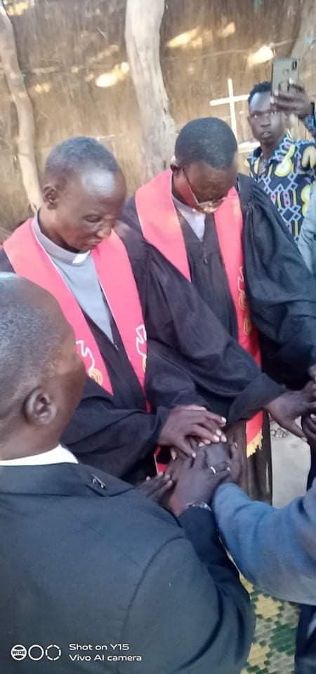 Rev. William Tut and Rev. James Maat lead prayer for the new pastors in Aweil.