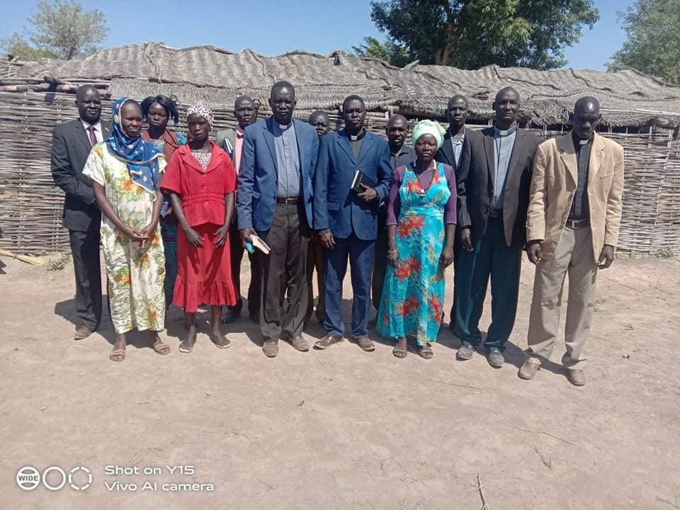 Pastors, elders, and deacons in Aweil stand in front of one of the churches.