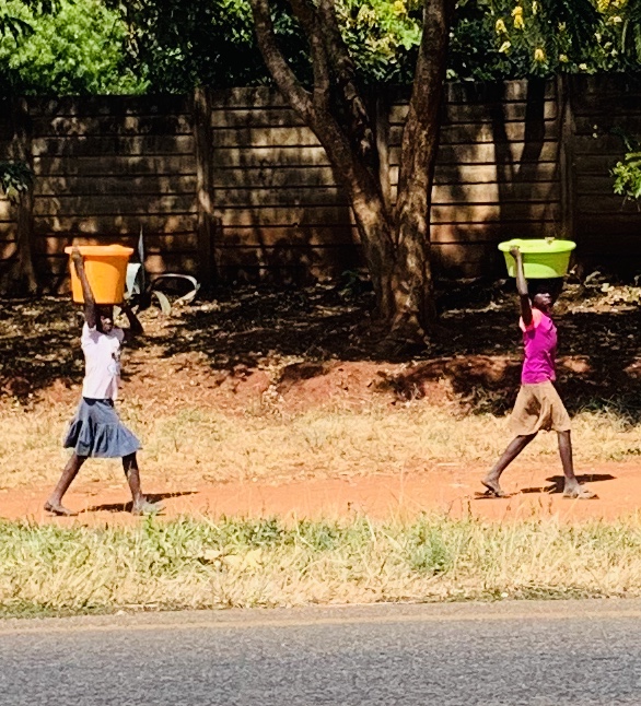 Young girls carrying water buckets for washing clothes