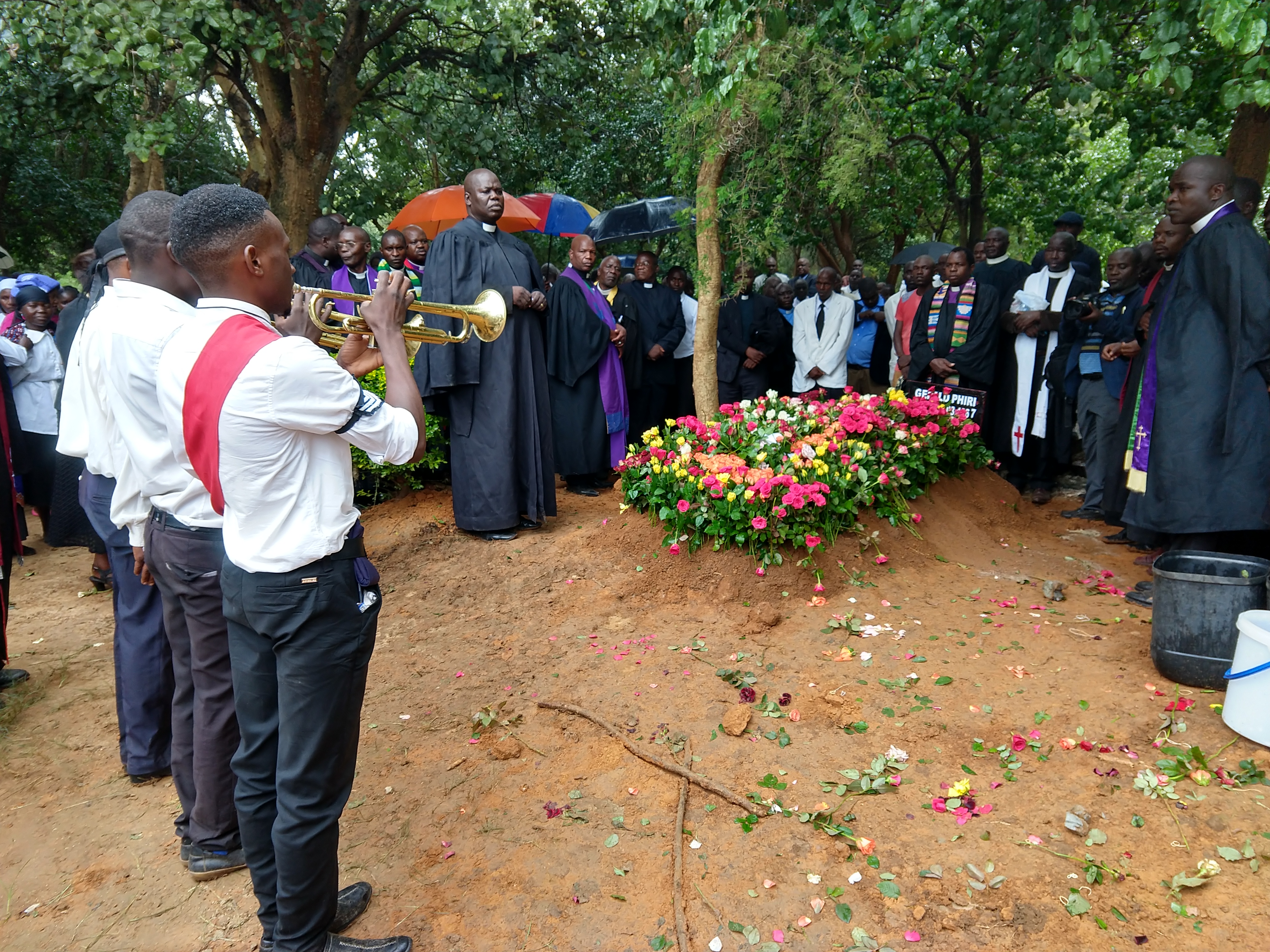 Final goodbye for Rev. Gerald Phiri. It is traditional for friends and loved ones to insert flowers into the earth covering the grave.