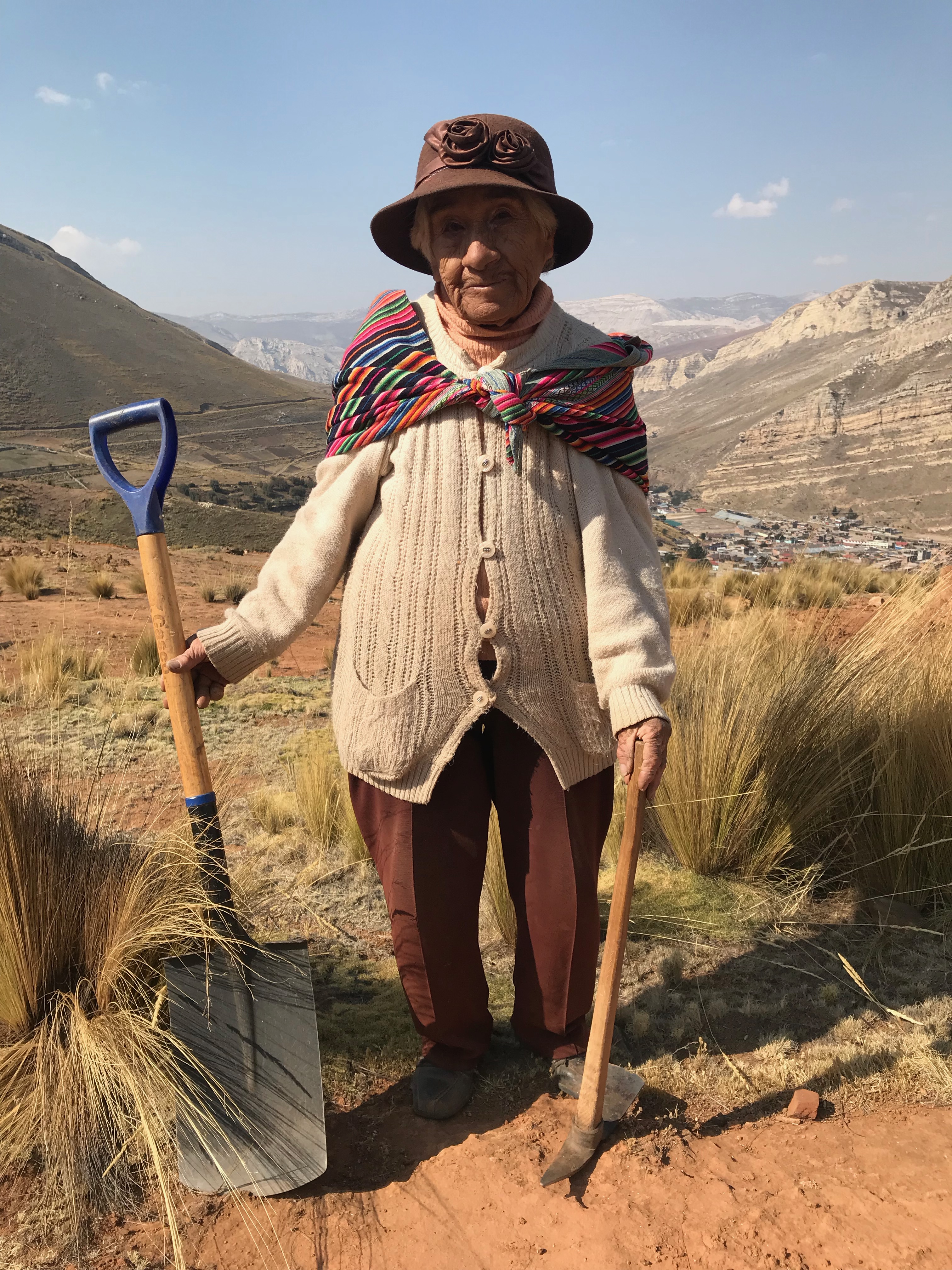 Victoria Trujillo, better known as Mama Toya, stands on the contaminated lands of her beloved Villa El Sol where she has spent the past twenty years planting over 30,000 trees. In the distant background are the mountains of La Oroya, white-washed from acid rain.