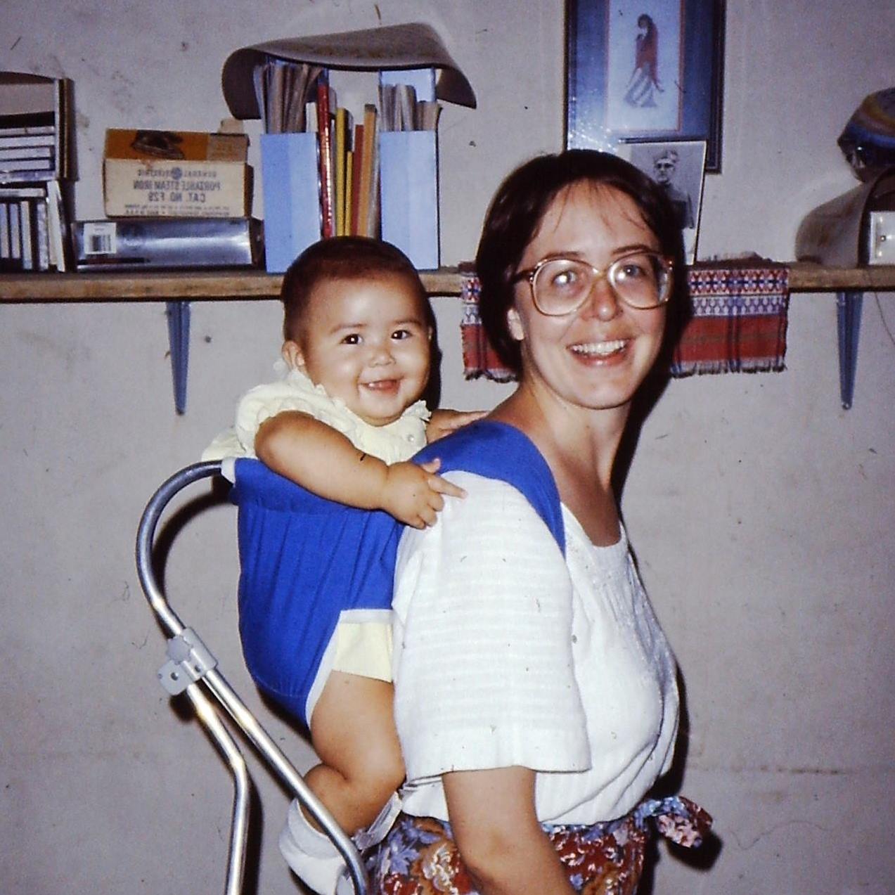 My daughter, Luz, in her Gerry carrier in our home in El Salvador. That was our mode of transportation then — walking and riding buses and in the back of pick-up trucks. Martyred Archbishop Romero is in a photo on the shelf behind us.