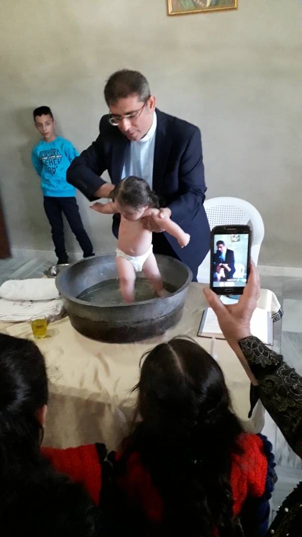 Salim baptizes an infant girl with Down syndrome.