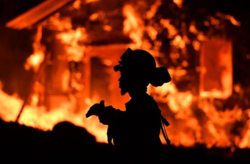 firefighter w burning house in back