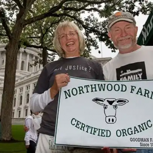 Jim and wife holding dairy farm sign