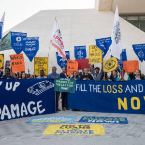 Group of protestors at COP28 hold blue Loss and Damage signs