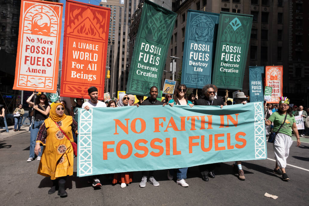Various faith community members march with banners discouraging fossil fuel use